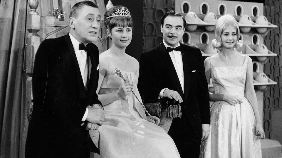L'animateur Roger Baulu prend la pose avec Marie-Claude Lévesque qu'on voit assise sur un trône coiffée d'un diadème, l'annonceur Henri Bergeron et l'hôtesse Lucie Gauthier.