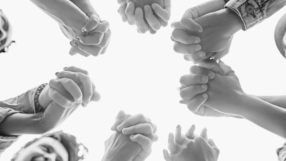 Un groupe de personne se tiennent les mains en cercle.
