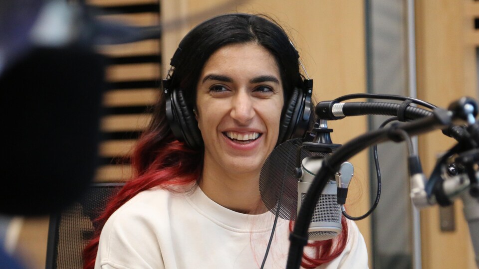 Une femme souriante regarde dans la direction de l'animateur dans un studio de radio. 