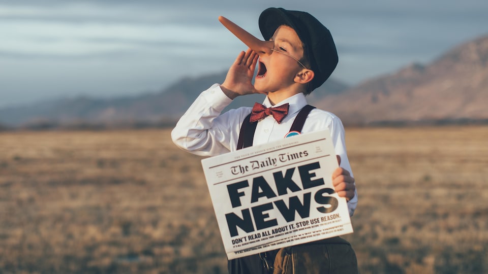 Un garçon, vêtu de vêtements d'antan, tient un journal en main sur lequel on peut lire «fake news». Il porte aussi un pastiche sur le nez qui rappelle Pinocchio.