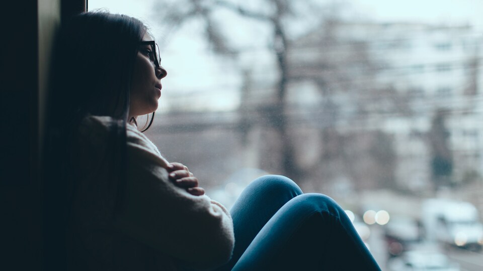 Image bleutée d'une jeune femme déprimée.