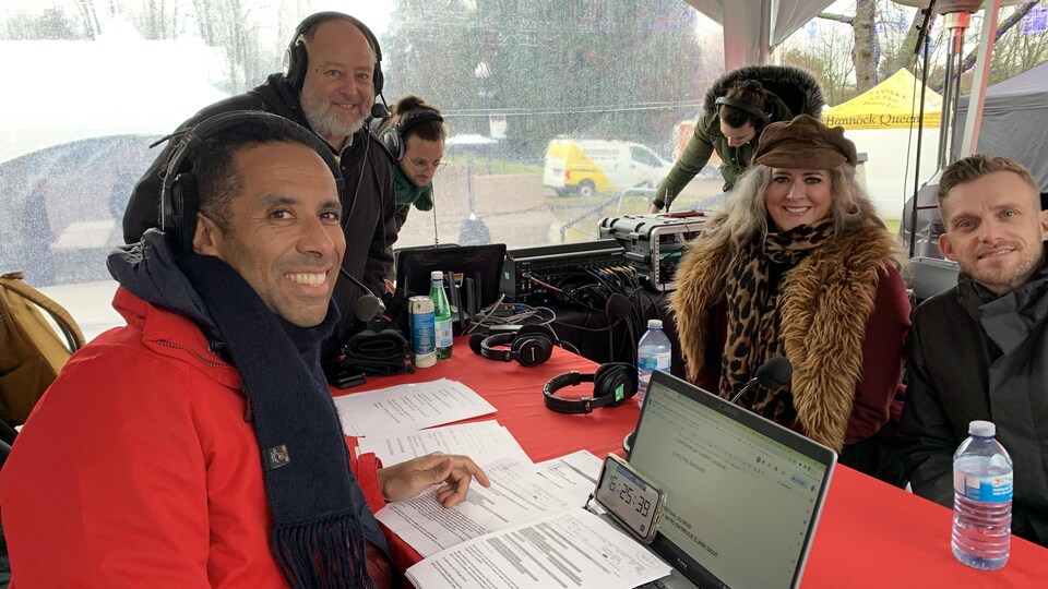 Trois hommes et une femme assis autour d'une table posent pour une photo au cours d'une entrevue radio.