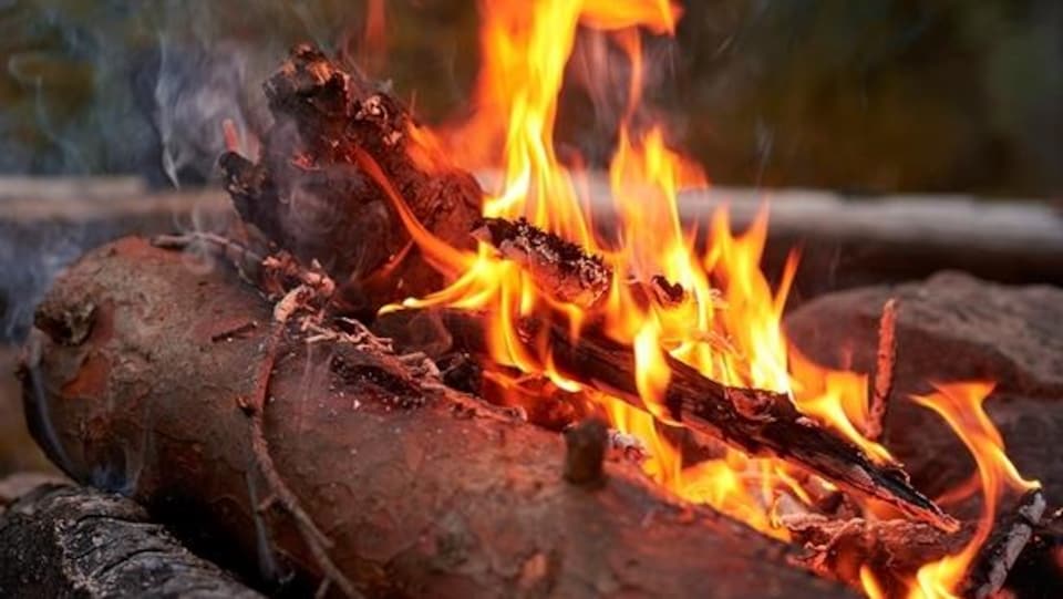 Une personne qui se réchauffe près d'un feu de camp.