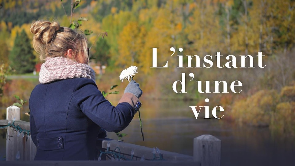 Une maman tient une fleur au bord d'une rivière en hommage à son enfant décédé pendant sa grossesse.