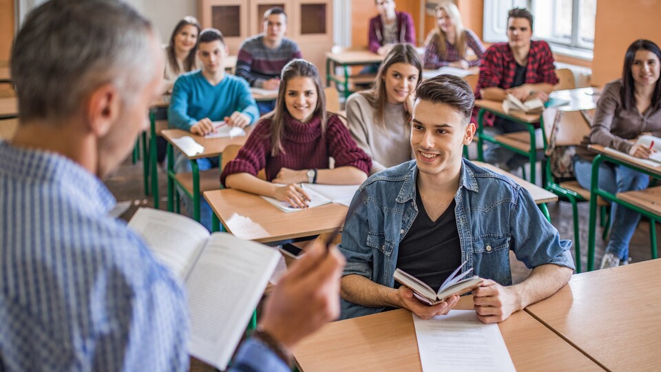 Un groupe de jeunes qui écoute leur professeur en classe. Un garçon en avant