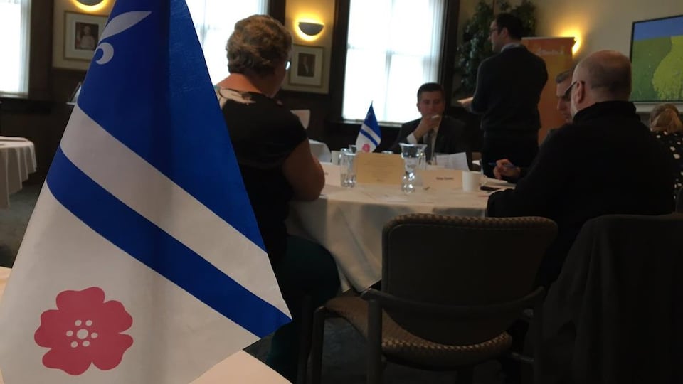 Le drapeau franco-albertain et des gens assis à une table.