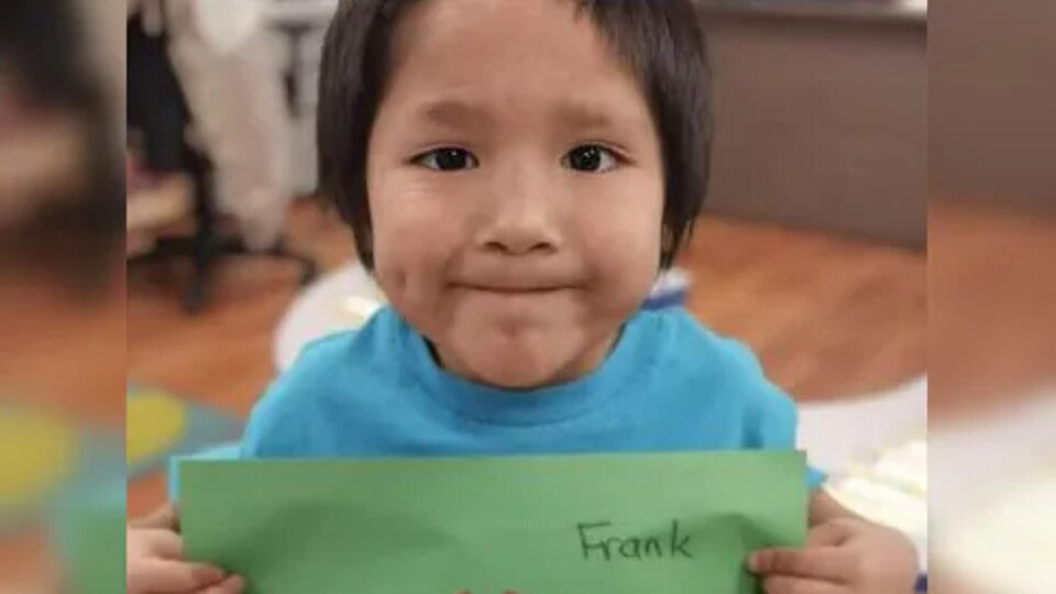 Le jeune Frank Young qui tient un dessin avec son nom sur la page.
