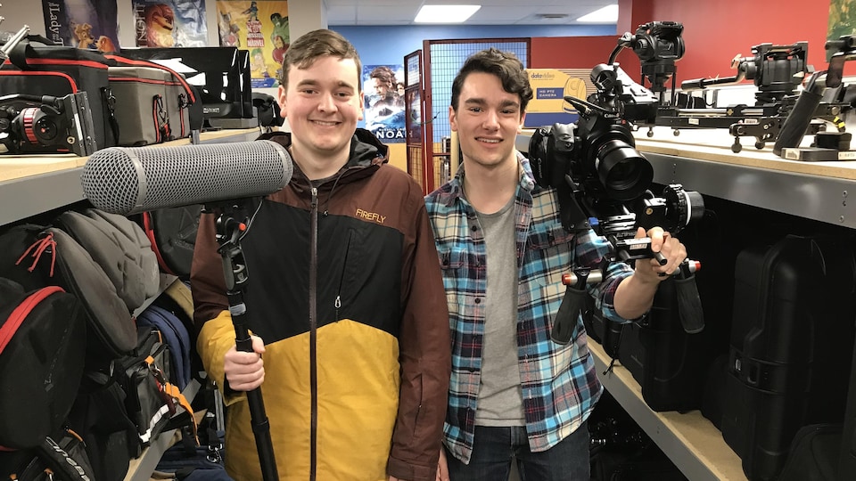 Deux jeunes hommes entourés d'équipement de cinéma.