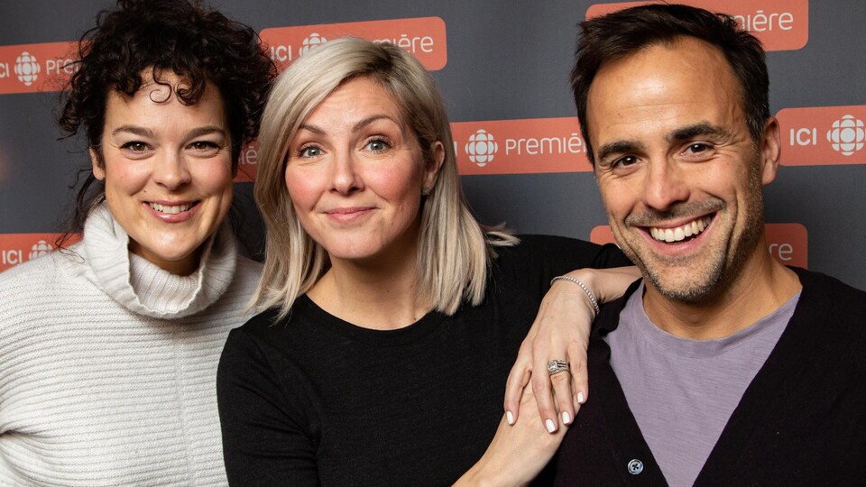 Les trois artistes sourient à la caméra.