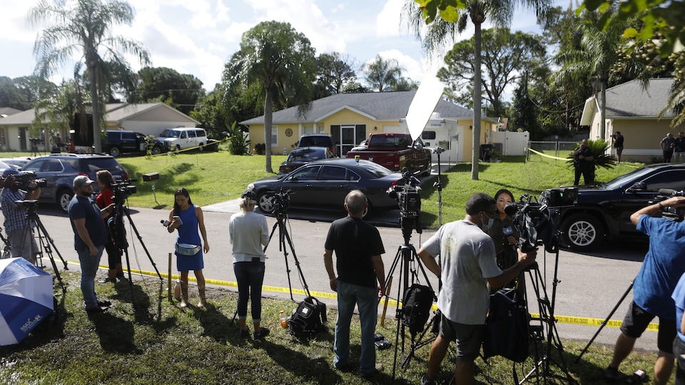 Des caméramans et des journalistes sont installés derrière un cordon de sécurité, de l'autre côté de la rue où se situe la maison de Brian Laudrie. 