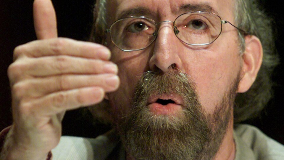 Gérald Larose parle en bougeant sa main droite devant lui.