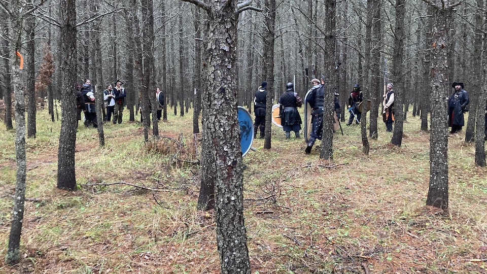 Une vingtaine de joueurs portant armure et bouclier se placent en deux équipes dans une plantation.