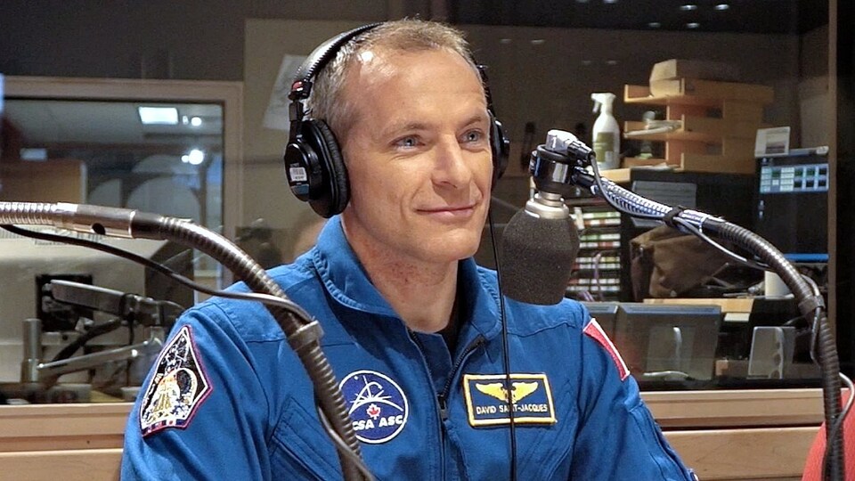 L'invité sourit derrière un micro vêtu de son habit d'astronaute.