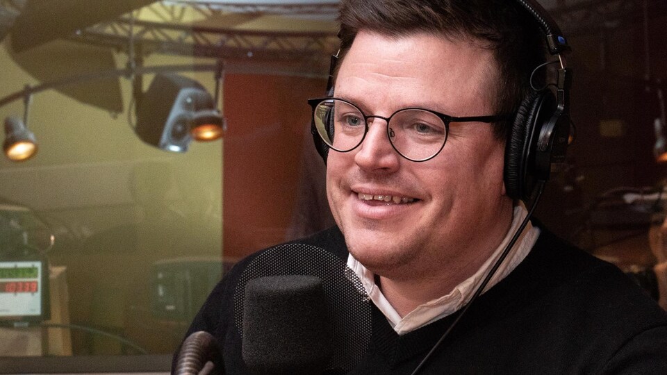Portant des lunettes, le créateur culinaire sourit à l'animateur.