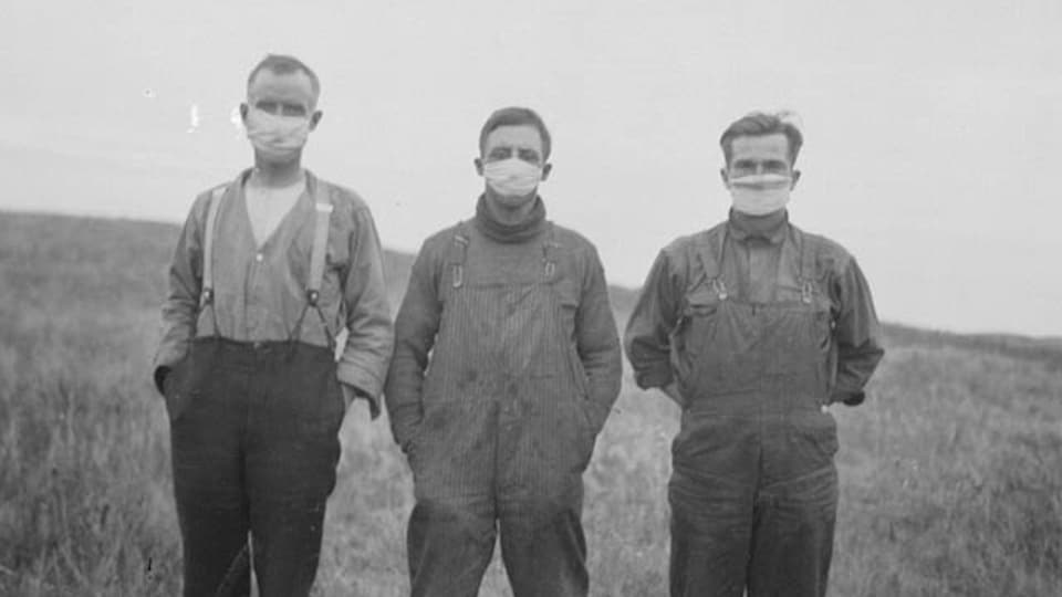 Photo en noir et blanc montrant trois hommes dans portant chacun un masque en tissu.