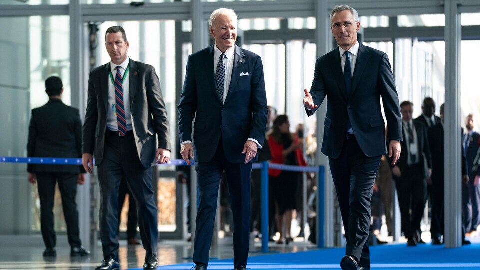 MM. Stoltenberg et Biden marchent sur un tapis bleu. 