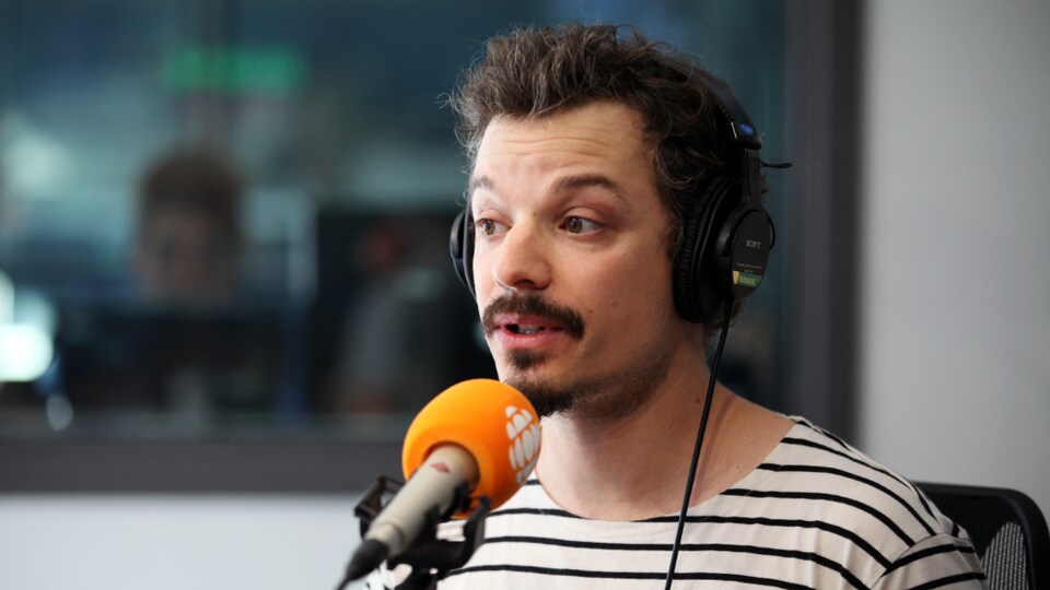 Le comédien Guillaume Pépin derrière un micro en studio.