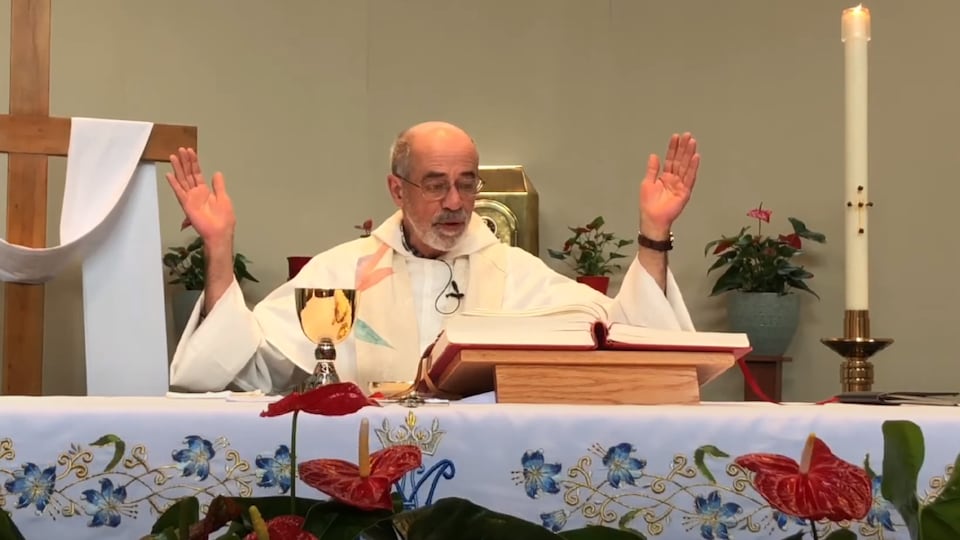un curé donnant la messe, lève les mains en l'air en lisant la Bible.