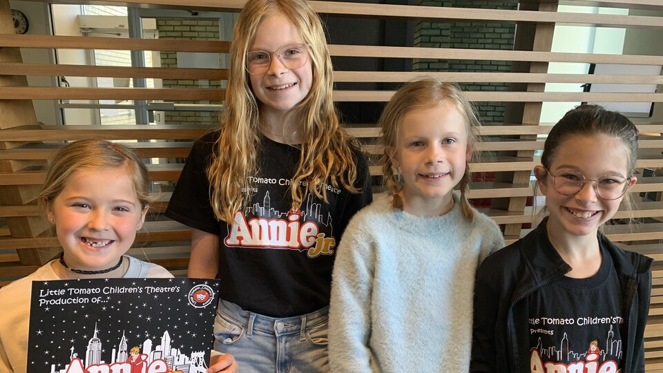 Charlie Walsh, Hannah et Kara Dick, Theresa Georges, quatre jeunes filles souriantes sont debout et portent des chandails de la comédie musicale 'Annie Jr.'