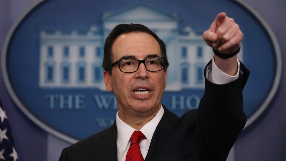 Steve Mnuchin, au cours d'un point de presse, montrant du doigt quelqu'un ou quelque chose.