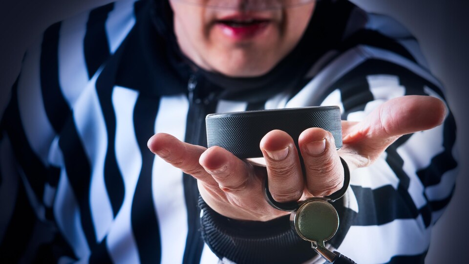 Un arbitre présente une rondelle de hockey