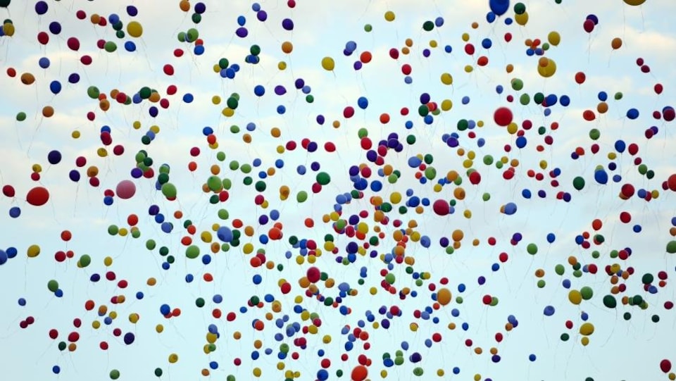 Une nuée de ballons gonflés à l'hélium dans le ciel. 