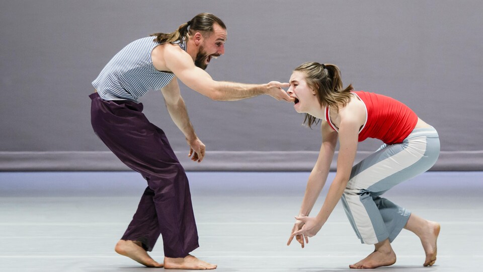 Sur la scène, un danseur et une danseuse ont la bouche grande ouverte et sont penchés en performance.