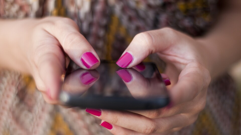 Des mains de femmes tiennent un téléphone intelligent.