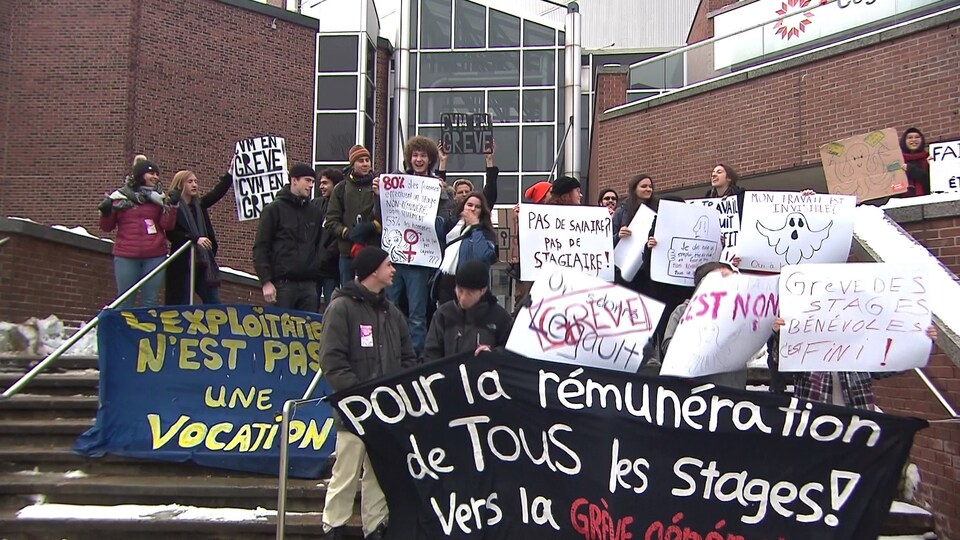 Des étudiants brandissent des affiches devant le Cégep du Vieux-Montréal.