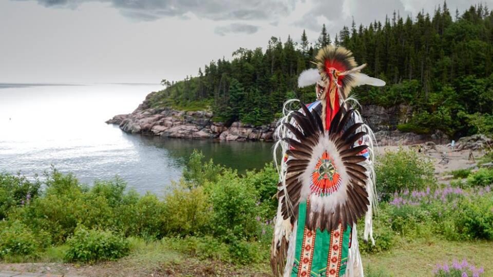 Un homme vêtu d'un costume traditionnel autochtone près du fleuve Saint-Laurent, à Essipit.
