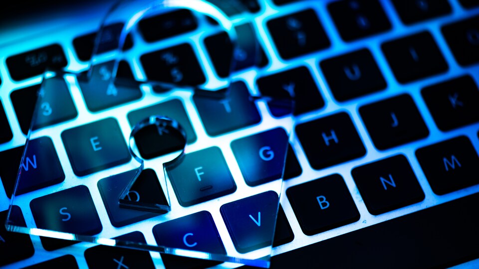 Un gros plan du clavier d'un ordinateur avec un cadenas transparent déposé dessus.