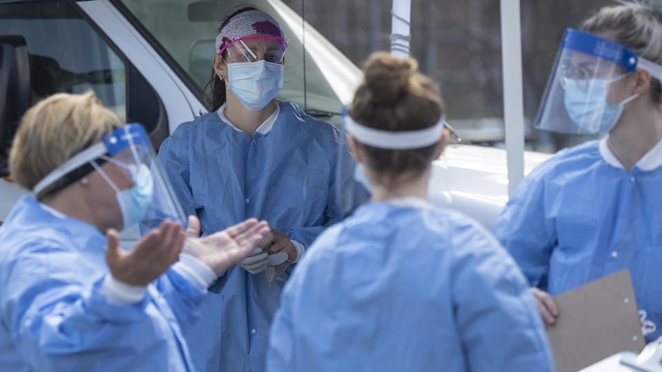 Des professionnelles de la santé portant leur blouse bleue et un masque.
