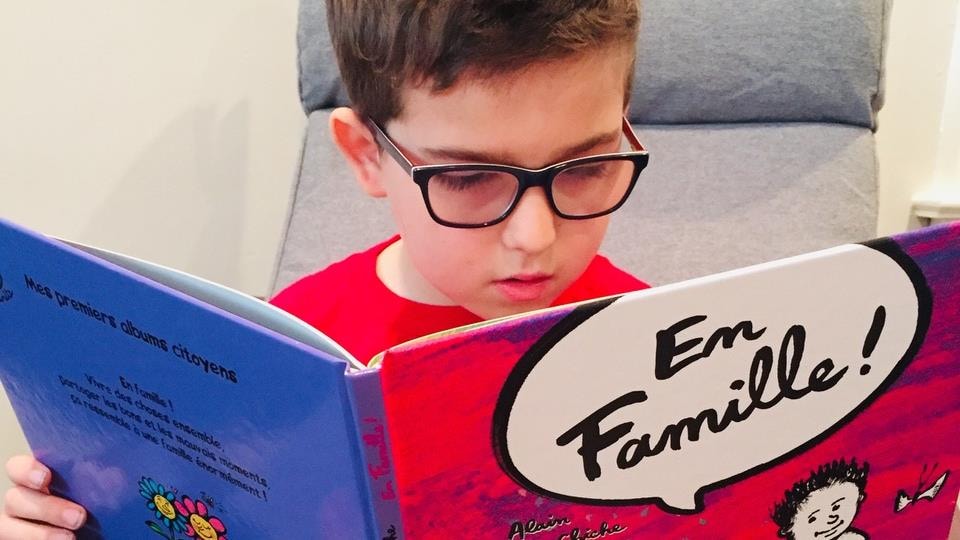 Le jeune Émile lit le livre « En famille ».