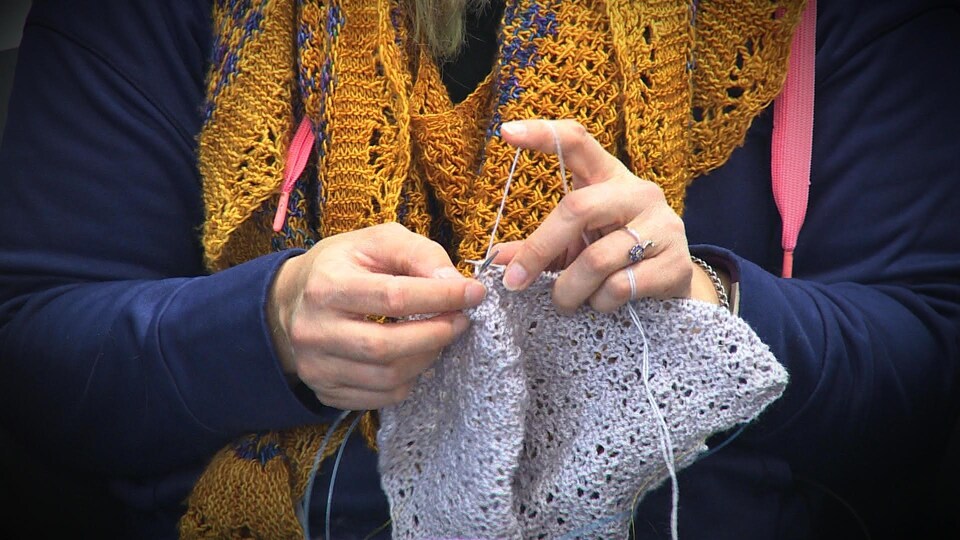 Gros plan sur les mains d'une dame qui tricote.