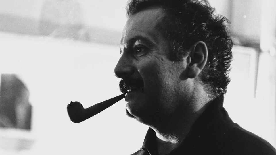 Georges Brassens avec une pipe à la bouche.