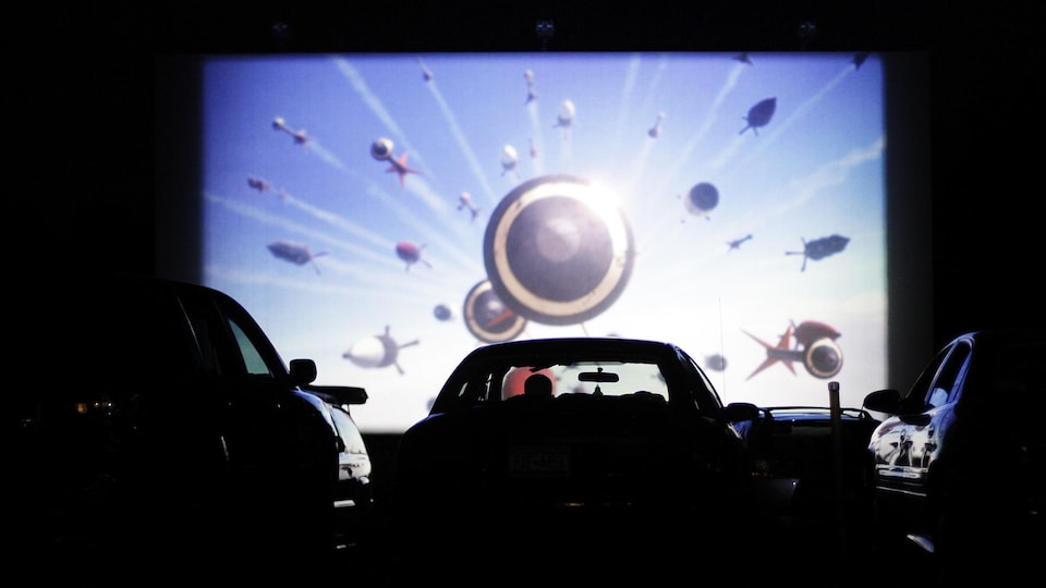 Une personne regarde un film dans sa voiture dans un ciné-parc.
