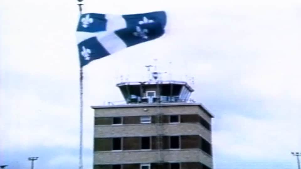 Drapeau québécois devant un centre de contrôle aérien.