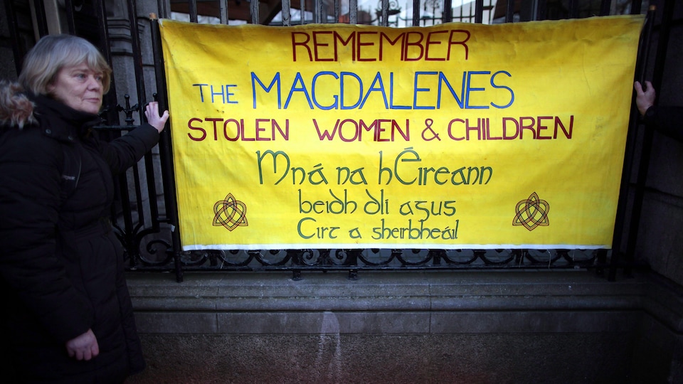 Une femme tient une pancarte en souvenir des victimes des couvents de la Madeleine.