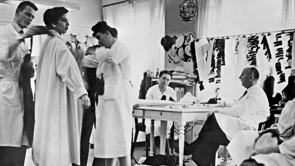 Des employés s'affairent autour du couturier Christian Dior en 1956.