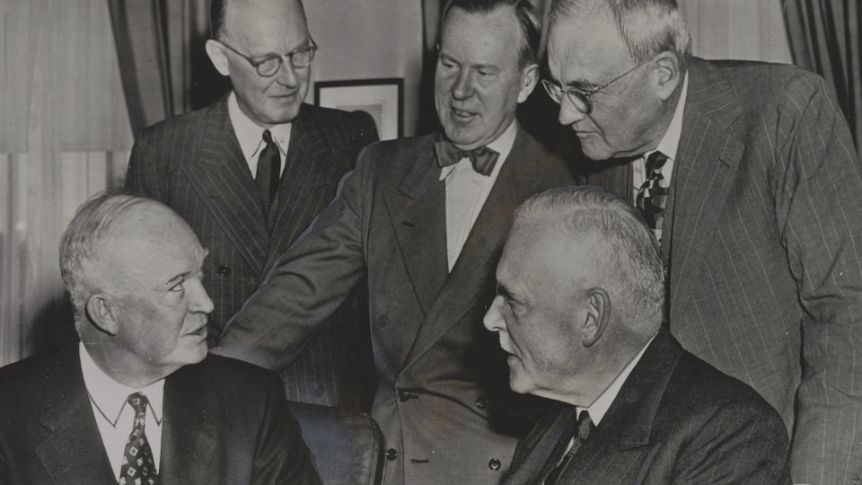 Le premier ministre Louis St-Laurent (en bas à dr.) rend visite au président Eisenhower (en bas à g.). Avec eux se trouvent l'ambassadeur canadien Hume Wrong, le ministre des Affaires étrangères Lester B. Pearson et le secrétaire d'État américain John Foster Dulles.