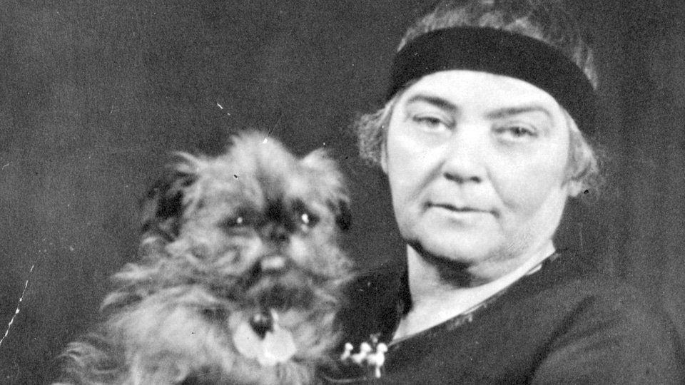 Emily Carr tient son chien dans ses bras.