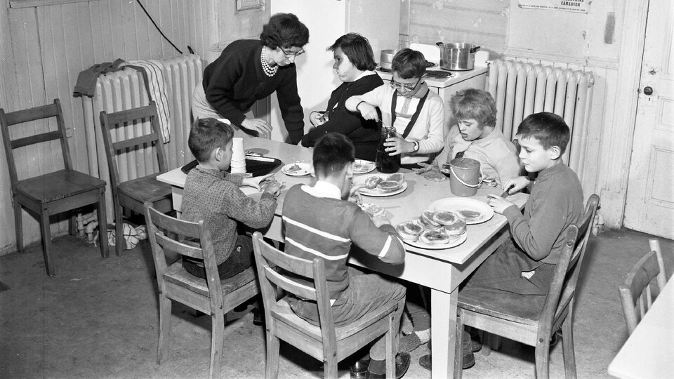Une femme aide lors d'un repas six enfants handicapés.