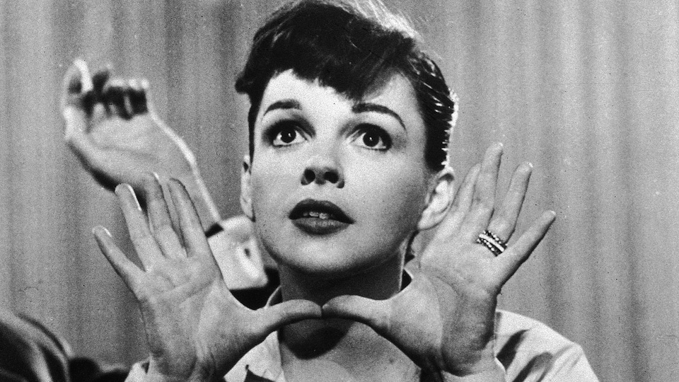 Judy Garland regarde au loin, ses deux mains ouvertes entourant son visage.