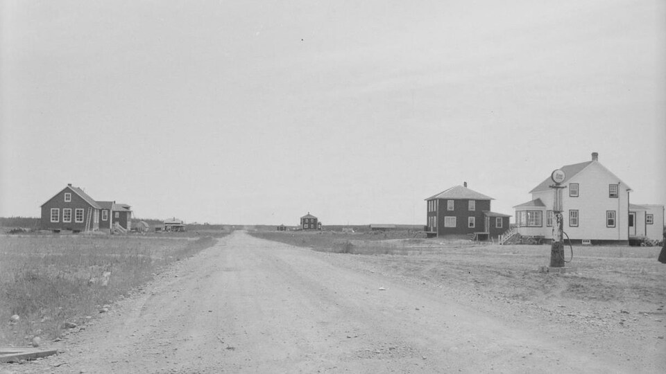 Quelques maisons isolées de chaque côté d'une route de terre.