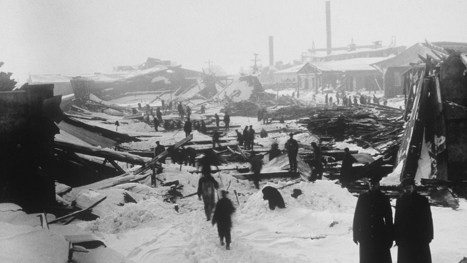 Des gens s'affairent parmi des débris et des immeubles démolis dans le port d'Halifax.