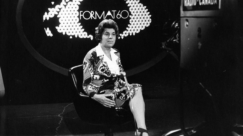 Photo en noir et blanc d'une femme assise sur le plateau d'une émission de télévision intitulé Format 60 et qui regarde une caméra de télévision.