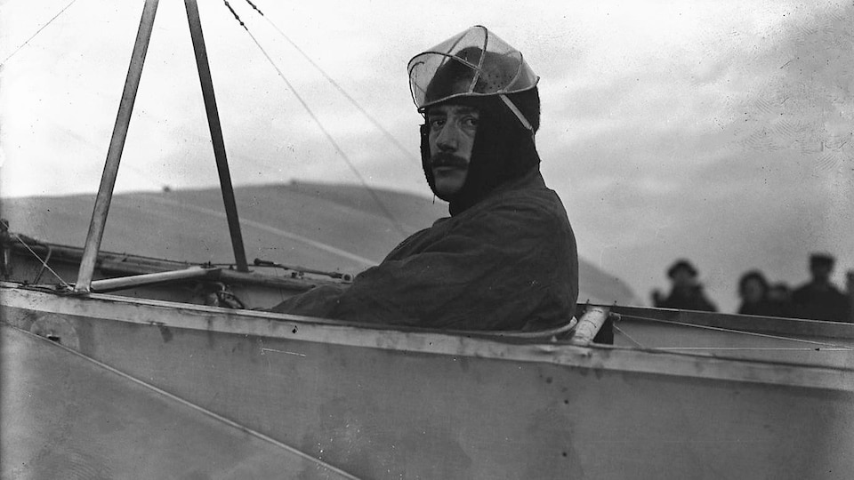 Photo de 1909 montrant Jacques de Lesseps, de profil, assis aux commandes d'un avion au sol.