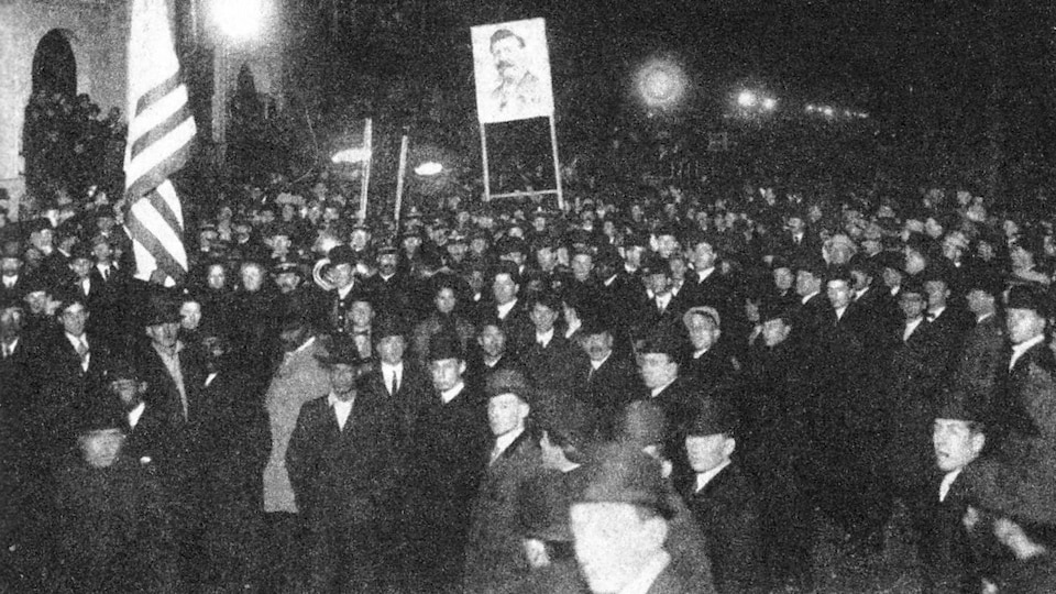 Attroupement d'hommes tenant  drapeaux, flambeaux et pancartes en 1909.