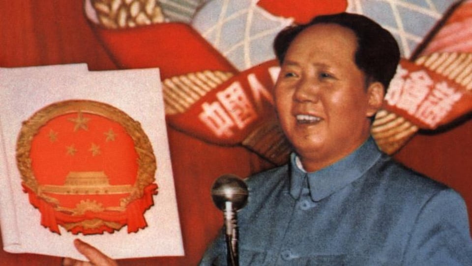 Devant deux micros, Mao Zedong tient une feuille en souriant.