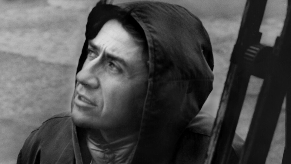 Le cinéaste Alain Resnais dans un manteau à capuchon.